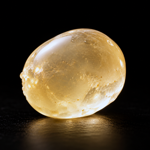 Translucent golden Chios mastic resin oil sphere on a black background