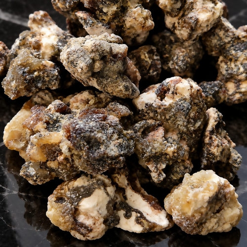 Assorted rough Mexican Black Copal Resin pieces with amber, cream and dark textures on black stone