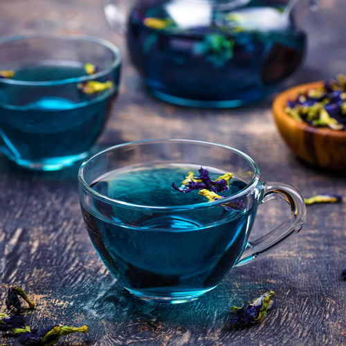 Clitoria ternatea butterfly pea flower tea served in clear glass cups with a blue infusion and teapot