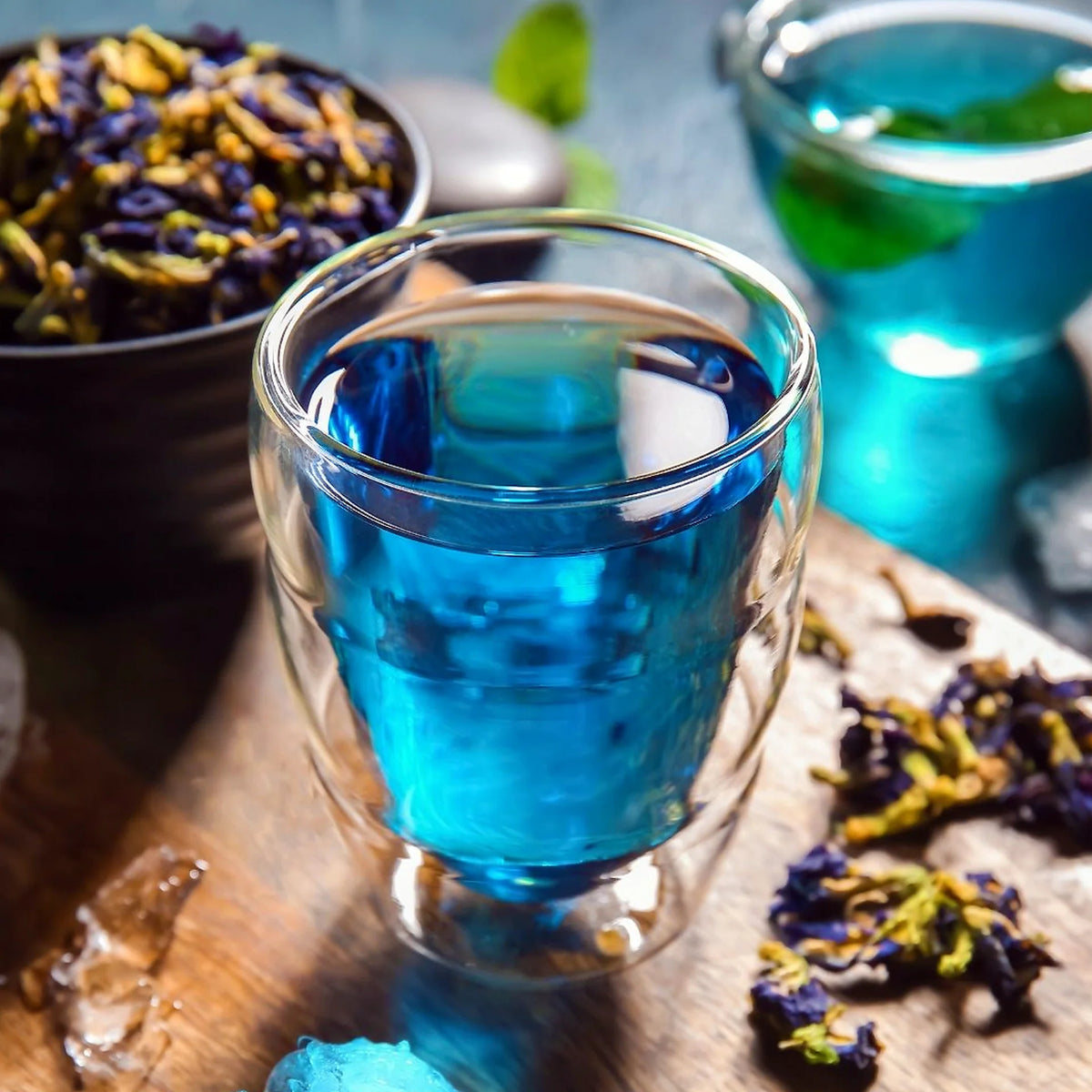 Clitoria ternatea butterfly pea flower tea bright blue infusion in a clear glass with dried flowers