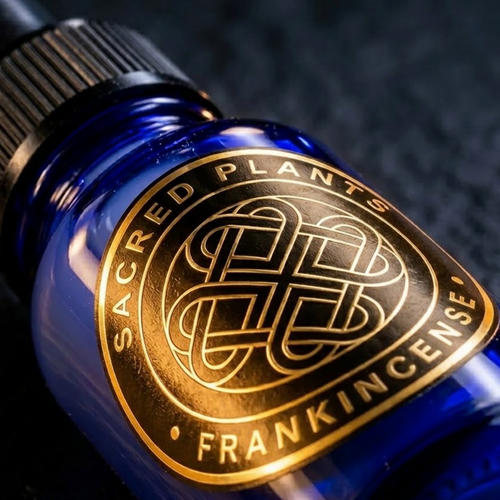Close-up of the Sacred Plants Australia gold-foil Frankincense label on a cobalt-blue glass dropper bottle against a dark studio background
