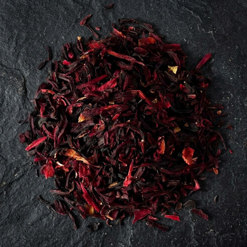 Dried Hibiscus × rosa-sinensis flower petals on a dark stone surface