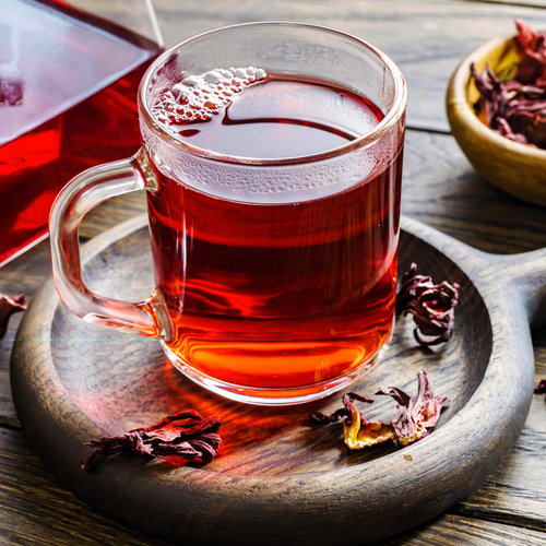 Brewed Hibiscus × rosa-sinensis flower tea in a clear glass cup showing a ruby-red infusion