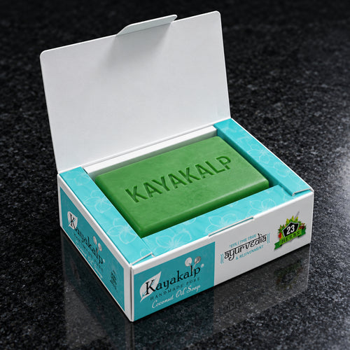 Kayakalp Ayurvedic coconut oil soap with 23 herbs presented inside its open turquoise retail box on polished black stone