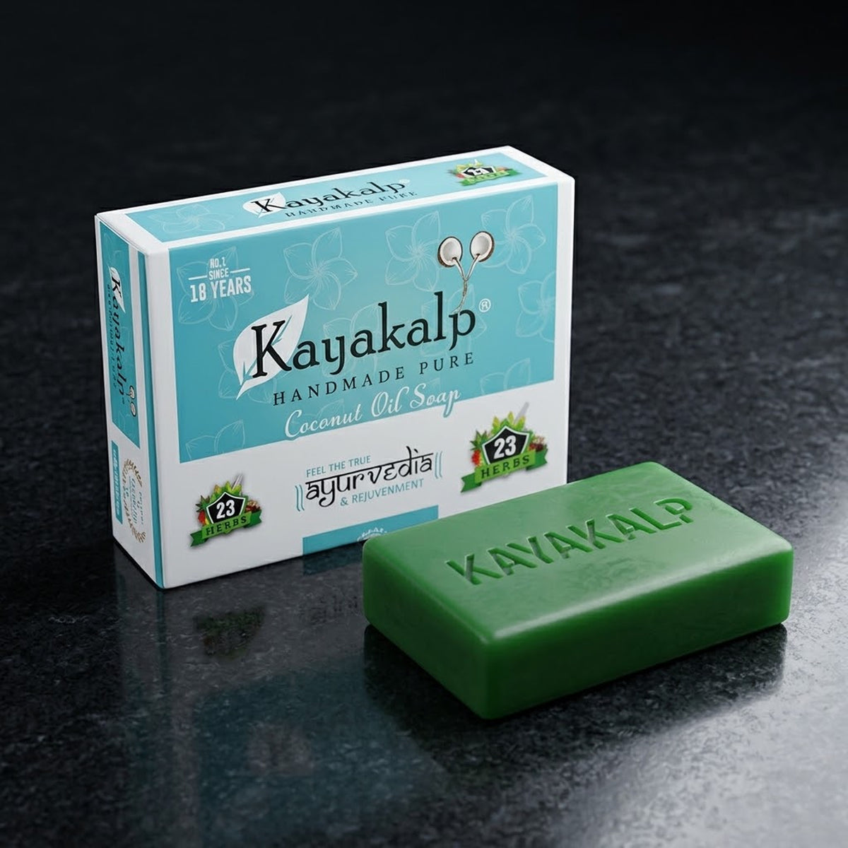 Kayakalp Ayurvedic coconut oil soap with 23 herbs, branded turquoise packaging beside the embossed green soap bar on dark stone