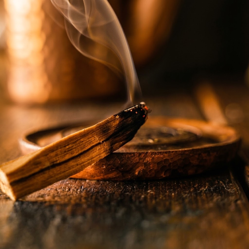Peruvian Palo Santo stick smouldering over a copper bowl