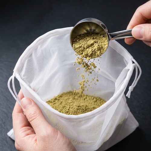 Ground Piper methysticum kava root powder being added with a stainless-steel scoop to a white nylon kava strainer bag.