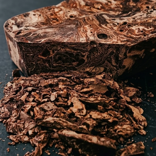 Close-up of marbled Peruvian ceremonial cacao mass with grated cacao shavings on a dark stone surface