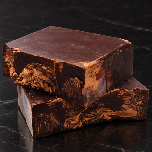 Two marbled cacao mass blocks on dark stone