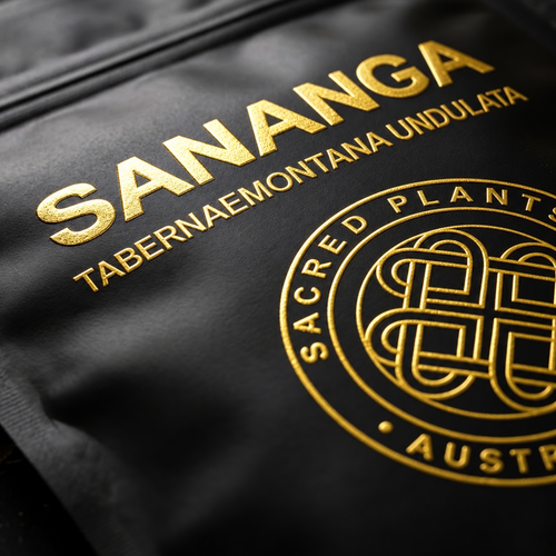 Ultra-macro of reflective gold-foil SANANGA lettering, Tabernaemontana undulata botanical name and a partially cropped Sacred Plants Australia medallion on a black mylar pouch.