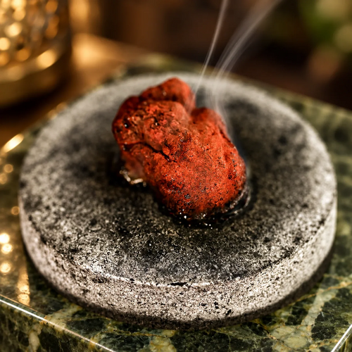 Socotra dragon’s blood resin warming and releasing smoke on an incense heater.