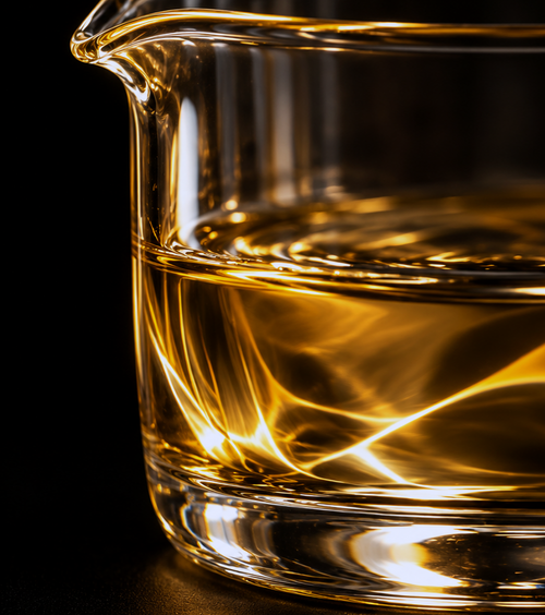 Extreme macro photograph of golden aromatic liquid in a clear glass vessel against a black background