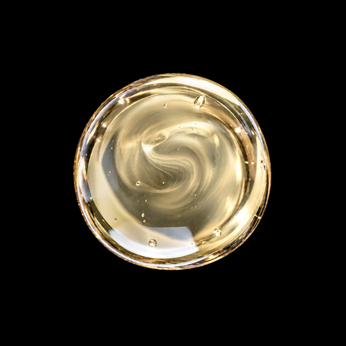Peruvian Palo Santo Wood Infused Oil — pale golden oil swirl overhead macro on black