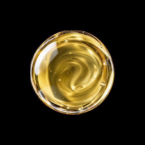 Vanuatu Nangai Oil — golden nut oil swirl overhead macro on black