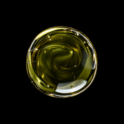 Vanuatu Tamanu Oil — deep olive-green oil swirl overhead macro on black